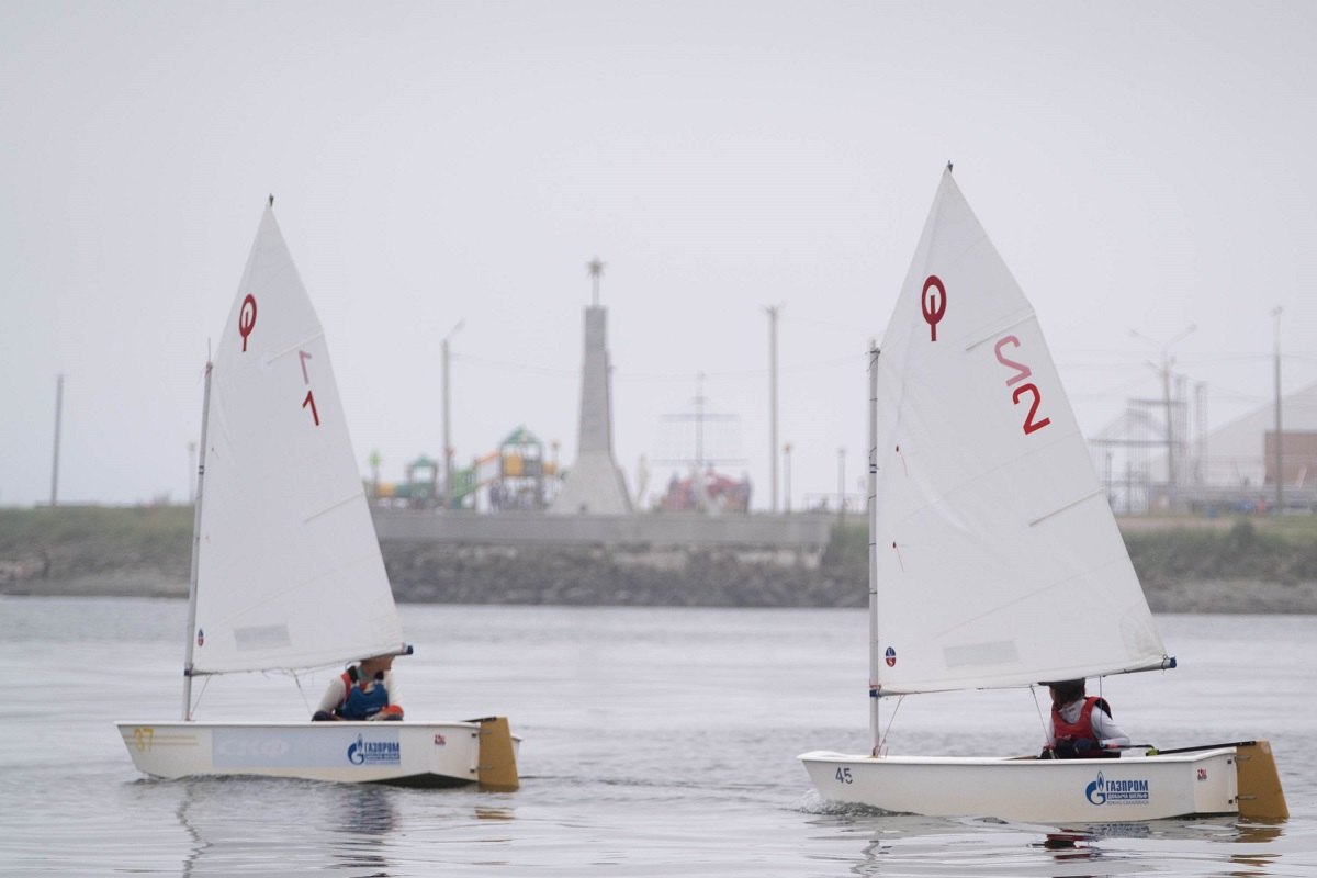 Regatta-Teilnehmer vor dem Hintergrund der Uferstraße in Cholmsk