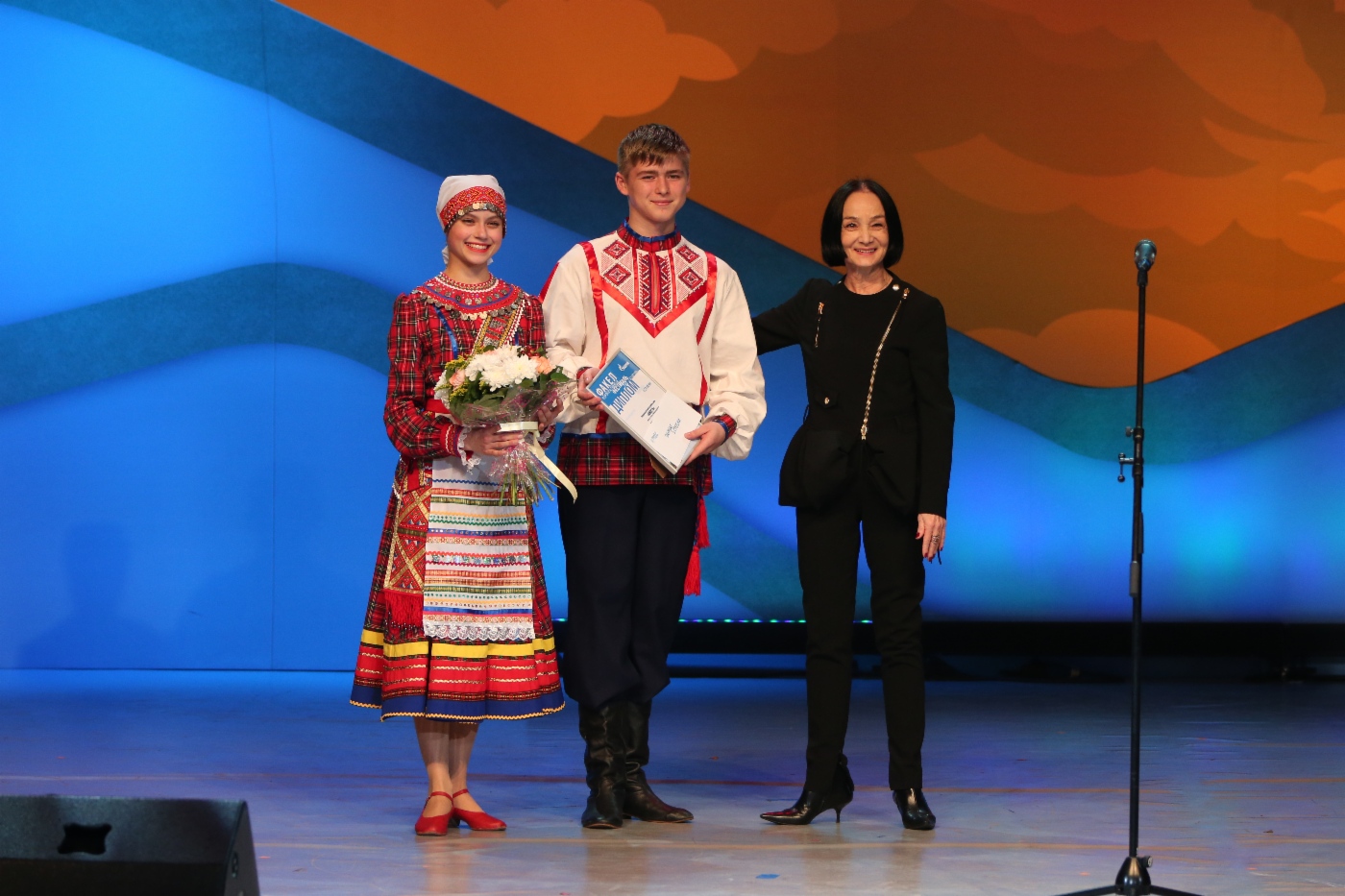 Jurorin Gyuzel Apanaeva (rechts) und Kinder-Volkstanzensemble Junost (OOO Gazprom Transgaz Nizhny Novgorod), 2. Platz in der Kategorie Volkschoreographie 